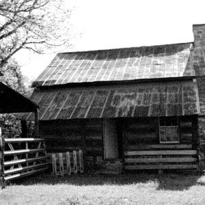 Log cabin with brick chimney and barn with gate