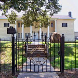 light colored two story building with columns and black wrought iron gate "Bauxite Museum"