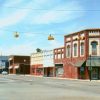 intersection with stoplights hanging on wires and a few two story brick buildings