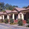 Single-story housing units with gabled roofs and covered porches on parking lot