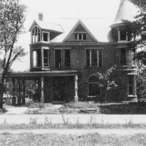 multistory stone Victorian style home with corner porch and turret