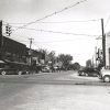 Multistory brick storefronts and parked cars on city street with traffic light hanging in the foreground