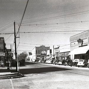 Multistory brick storefronts with signs power lines and parked cars on city street