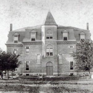 symmetrical multistory building with conical middle tower and trees