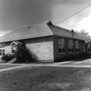 Single-story building with Dutch gable roof on grass with sidewalk