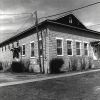 Single-story building with gabled roof on grass with sidewalk