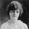 Young white woman with wavy hair and and glasses wearing lacy top