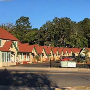 Multistory hotel building with identical housing units around parking lot on two-lane road