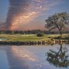 sunset with linear cloud formation over golf course and water hazard