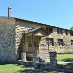 Brick building with two covered porches and wall with brick columns