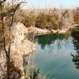 Flooded rock quarry surrounded by trees