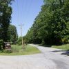 Two-lane rural road with turnoff under power lines with trees on right side