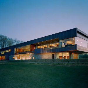 Narrow multistory modern building with brick and glass walls on grass