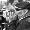 African-American man in hat and black sunglasses wearing rings playing harmonica into a microphone