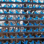 Hand-blown glass bluebird display on thin shelves outdoors with forest and mountains in background