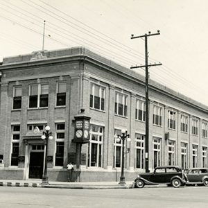 Multistory buildings on street corner with street lamps power lines and parked cars