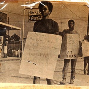 African-American woman and two men in line with protest signs at grocery store