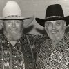 Two white men with beards smiling in colorful shirts and cowboy hats