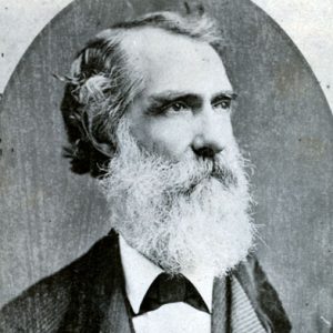 Old white man with long white beard in suit and bow tie