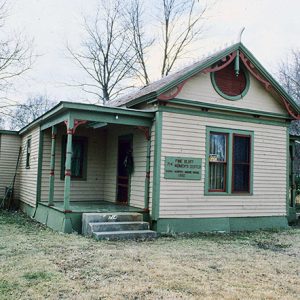 Small green and cream house with covered porch with red accents