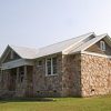 Wood and stone building with covered porch and four columns