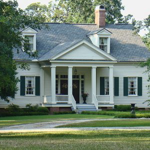 Two-story white house with dark shutters and four small columns on porch