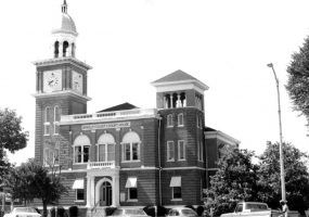 Brick building with clock tower and arched windows and arched entrances