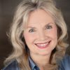 White woman with long hair smiling in blue shirt