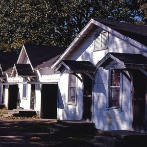 Identical housing units with pairs of front doors and windows and awnings over front steps