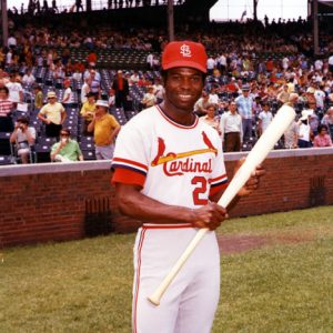 African-American man in a St. Louis Cardinals uniform posing with a bat in a crowded stadium