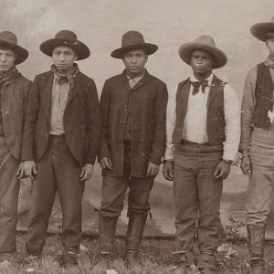 Group of Native American men in suits and hats standing in line