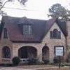 Two-story brick house with covered porch with archway hipped roof and arched doorway facing the street