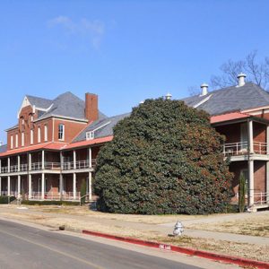 wide red brick multistory building with balcony running full width