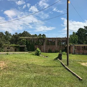 Dilapidated brick gymnasium building with vines growing on it