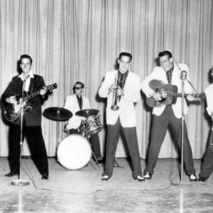 Young white men in suits playing musical instruments on stage