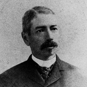 White man with mustache in suit and tie