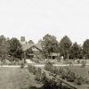 wooden building with water tower amid field with trees