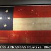 Red white and blue flag with three stripes and seven stars under glass