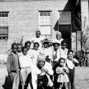 small group of African American students of various ages outside brick building