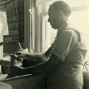 Older white man working at pottery wheel in shop