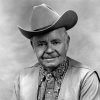 White man smiling in cowboy hat and western clothing