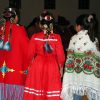 Three Caddo women in dresses and hair ornamentation photographed from behind