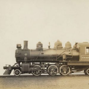 Side view of steam locomotive with coal car on railroad tracks