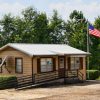 Single-story building with flag pole and wheelchair ramp on gravel parking lot