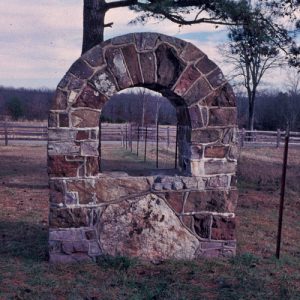 Arched stone block sign frame with fences and trees in the background