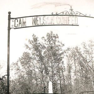 Locked cemetery gates with monument visible among the trees