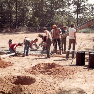 Group of white men with cement truck in a dirt field