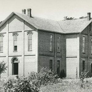 Two-story brick building with chimneys and arched doorways