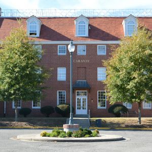 Multistory brick building with wings and street lamp in round flower bed in center of courtyard