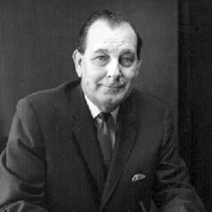 White man in suit and tie sitting at desk